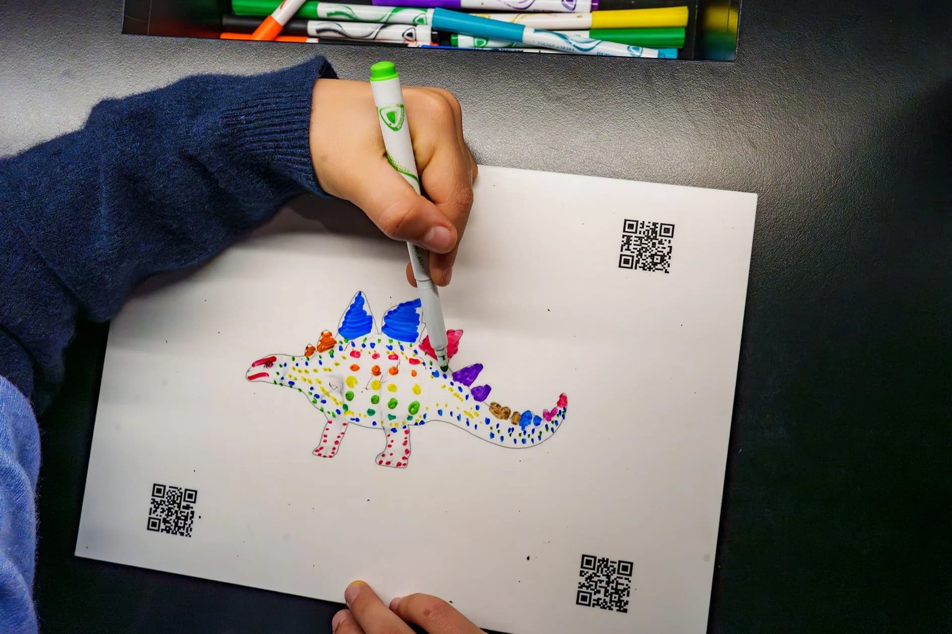 Enfant coloriant un template de stégosaure avec QR codes